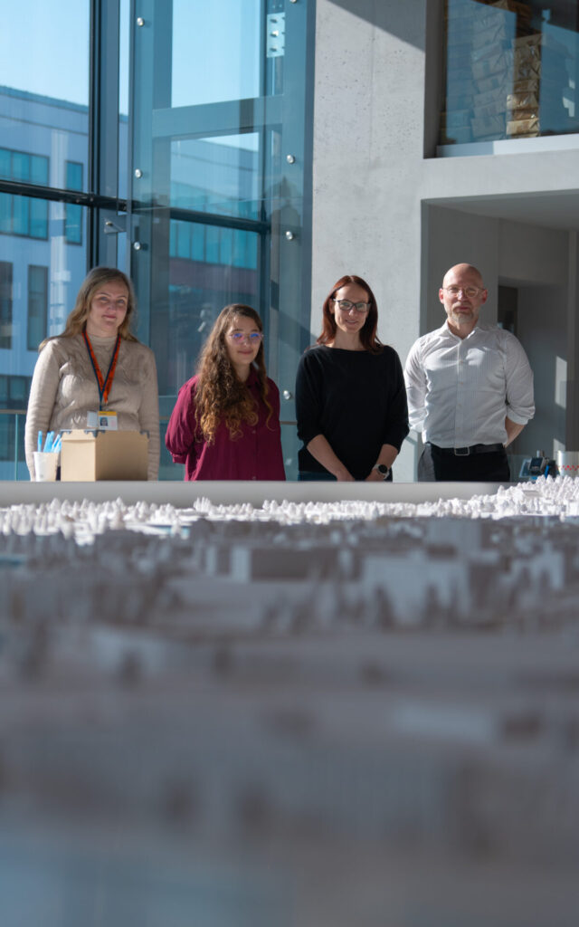 Trzy kobiety i autor projektu pozują do zdjęcia nad makietą Gdańska.